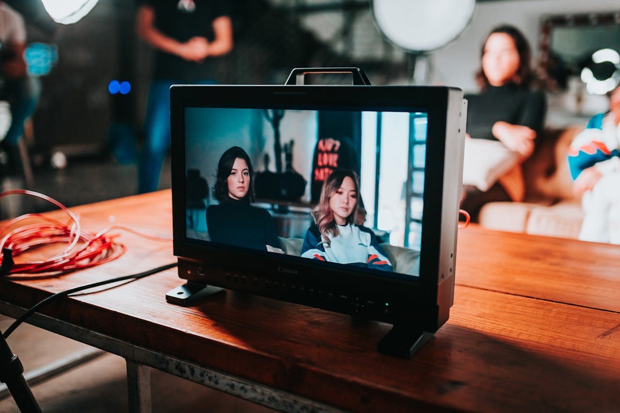 A professional photoshoot setup displaying two women on a monitor in a studio environment.